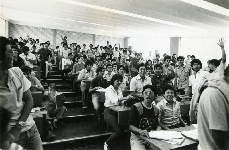Alumnos de Estudios Generales Ciencias posan para un retrato grupal en una de las clásicas aulas escalonadas, al final de su clase. Comienzos de los años ochenta. El ambiente es casi totalmente masculino.